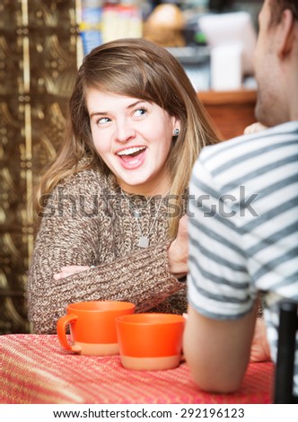 Cheerful Caucasian female laughing with friend in cafe