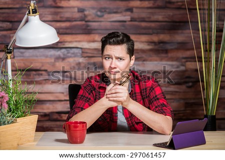 Woman wearing flannel shirt at desk with one eyebrow raised