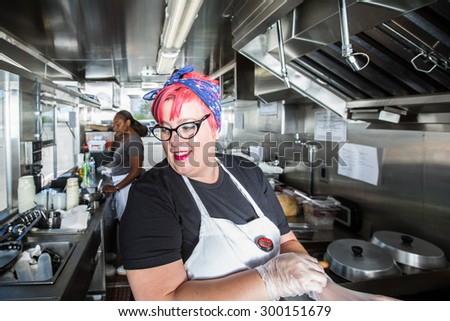 Pink haired chef puts on work gloves aboard busy food truck