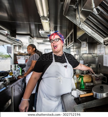 Chef with pink hair directs staff on food truck