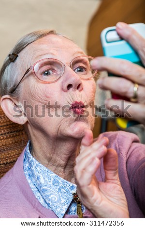 Happy elder woman taking duck face selfie