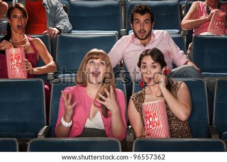 Group of amazed people watch movie in theater