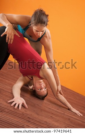 Yoga trainer helping student perform yoga stretching