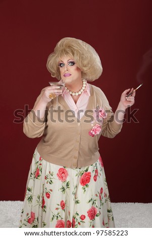 Drag queen holding cigarette and martini over maroon background