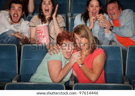 Group of scared people watching movie in theater