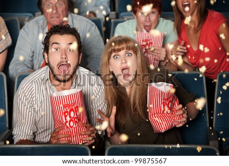 Group of frightened people watching movie spill popcorn