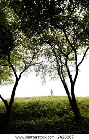 young boy sings on a green hill, wide angle perspective