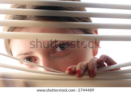 curious girl looking through roller-blind