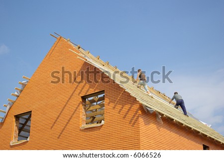 Construction workers placing the first section of roof on a new home under construction.