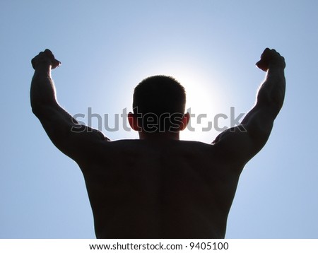A man stands on against a sun with heaved up hands
