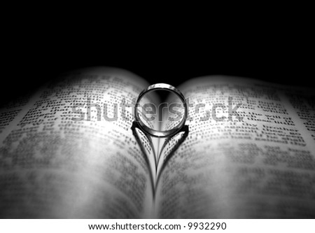Wedding Ring and heart shaped shadow over a Bible