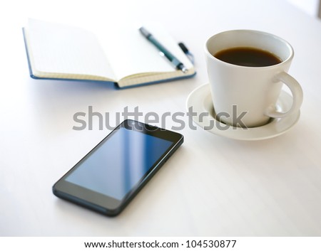 Smartphone close-up, coffee and planning book on the background