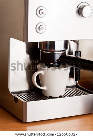 Metall coffee machine and cup of fresh coffee with foam