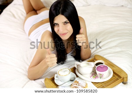 Elegant female model with beautiful green eyes showing thumbs up smiling in bed