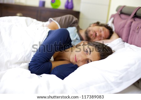 Depressed woman in bed while husband is sleeping not caring about her