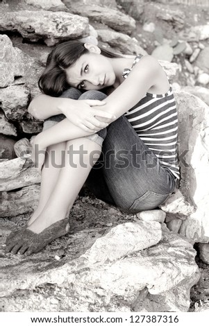 Depressed young woman sitting on rocks feeling lonely after divorce/Sadness in black and white