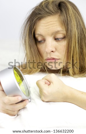 Beautiful blonde woman in bed fighting with alarm clock tired not able to sleep