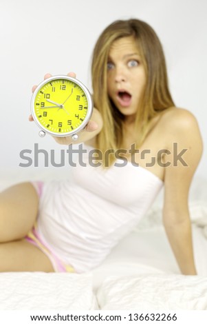 Beautiful woman showing alarm clock late for work stress