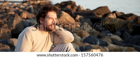 Sad man feeling alone observing sunset
