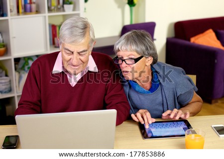 Senior couple writing emails on their notebook computer and tablet.