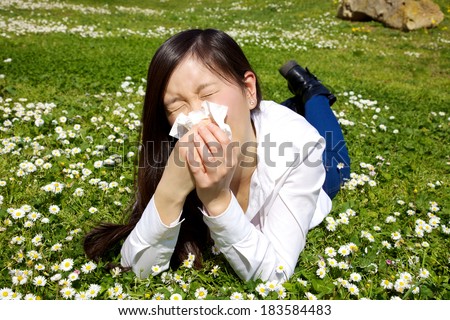 Sick chinese woman laying in grass with flowers