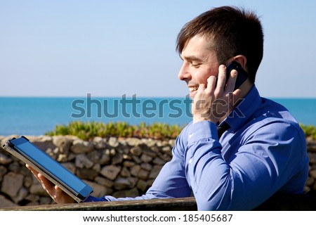 Cool man talking on the phone while working with tablet