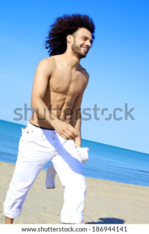 Athletic cool sexy italian man smiling happy on beach in summer