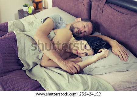 Unhappy sad woman in bed with sleeping boyfriend depressed