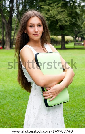 Happy female student holding notebooks and smiling outdoors.