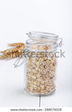 The oat flakes in jar on wooden table.