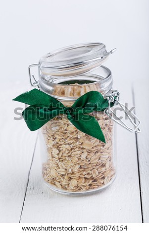 The oat flakes in opened jar on wooden table.