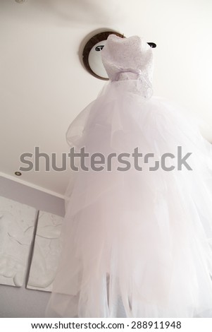 Wedding dress weighs on lamp in room.