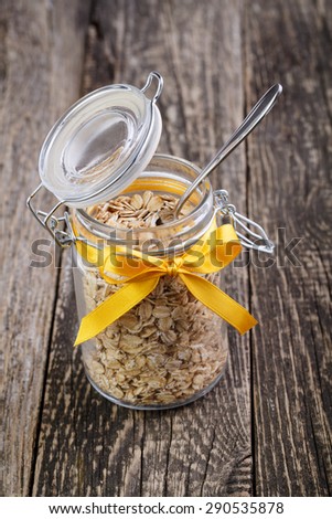 The oat flakes in glass jar with ribbon and spoon.