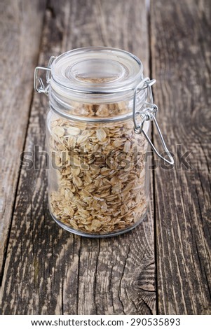 The oat flakes in glass jar on wooden table.
