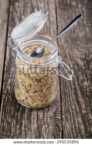 The oat flakes in glass jar with spoon.
