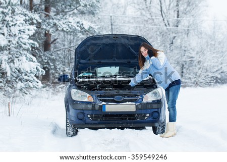 Winter car breakdown - woman try to repair motor.
