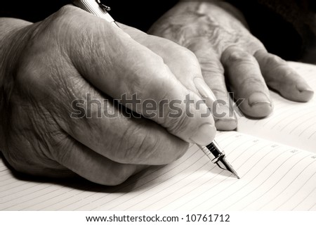 Old hands writing something with a pen in a notebook
