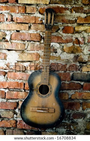 an old guitar on the brick wall