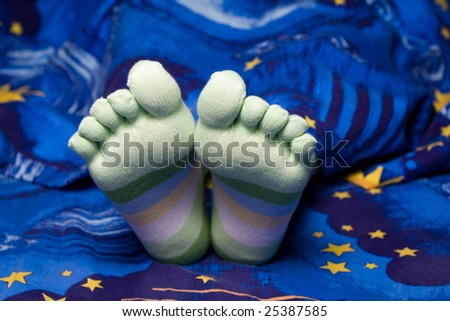 Stock photo: an image of funny feet in striped socks in bed