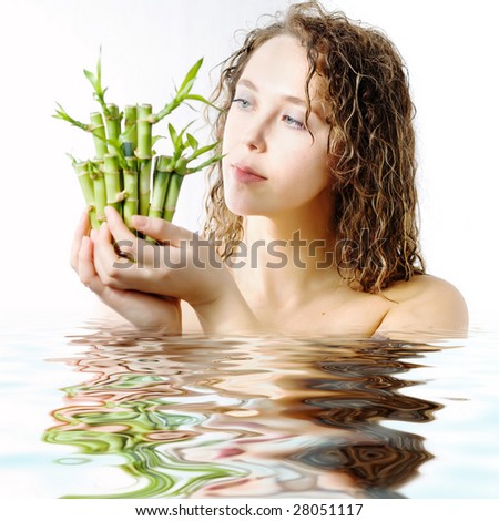 An image of a woman looking at green bamboo in her hands and water