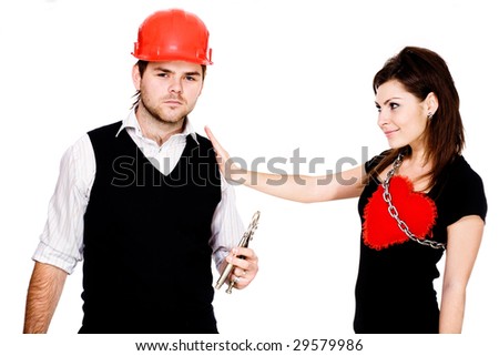 A sad man in a red helmet with pliers and a pleased woman with his heart tied to her breast by a metallic chain