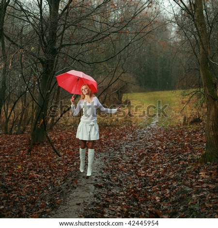 A woman with a red umbrella in autumn park