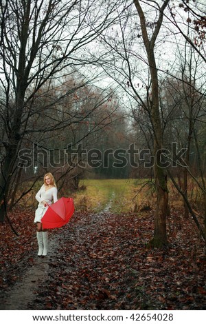 A woman with a red umbrella in autumn park