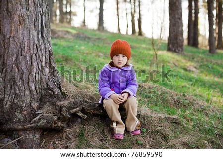 An image of a little girl in a red cap in the forest