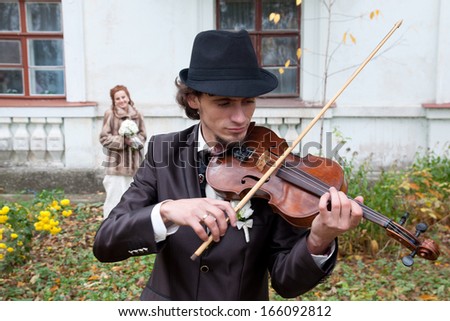 Image of a groom playing violin outdoors