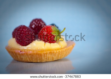Pastry with vanilla and wild-berries on blue background,
