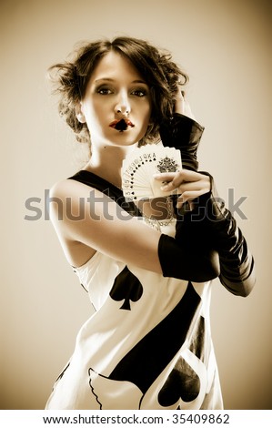 Beautiful woman holding spade cards in hand. spade on lips. fashion photo.