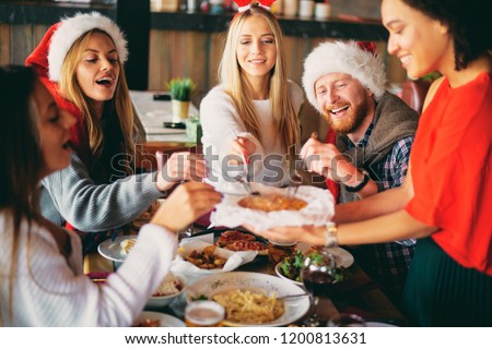 Friends having dinner at home at Christmas eve. Winter holidays concept.