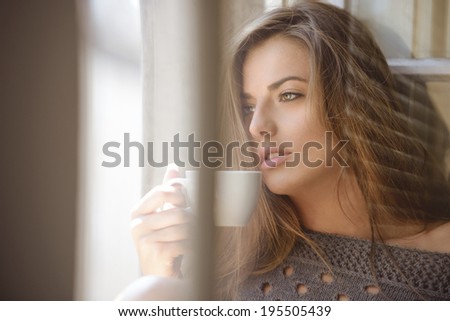 beautiful woman drinking coffee in the morning sitting by the window.