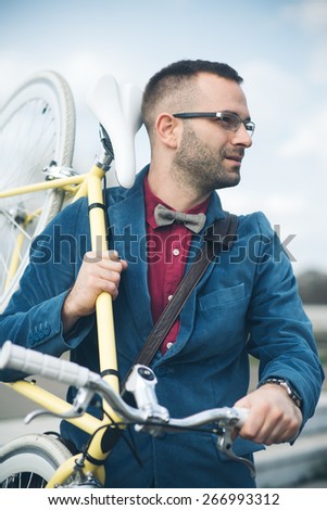 Young stylish man holding fixed gear bicycle walking in the city, handsome hipster man walking, fashion model man posing with fixed gear bicycle
